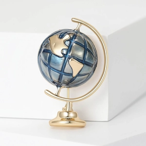 Globe brooch with golden frame and blue sphere on a minimalist white background