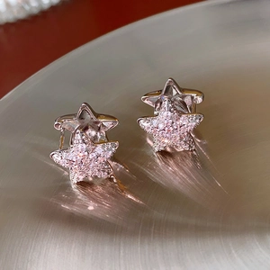 Close-up of star-shaped earrings in silver metal with sparkling pink zircon pavé