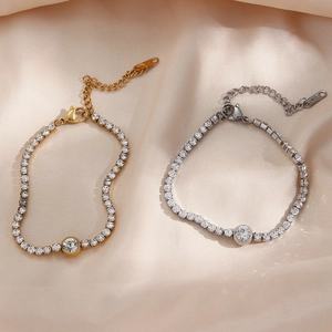 Close-up of gold and silver tennis bracelets with round zircon on silk fabric