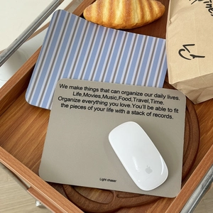 Close-up of leather office mouse pads in coffee and striped patterns on a wood tray