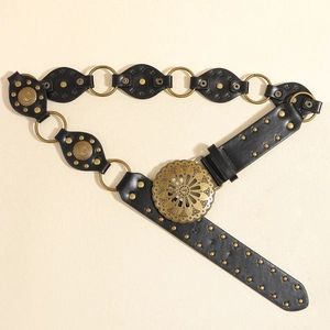 Détail d'une ceinture en cuir noir avec rivets bronzes et grande boucle bohème ciselée
