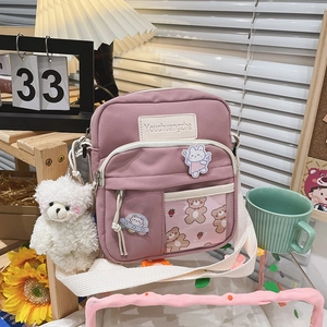 Détail du sac bandoulière rose avec breloque ours et écussons de dessin animé