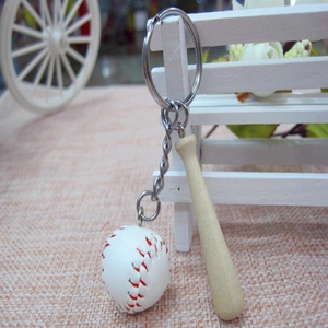 Detail of mini wooden baseball bat and leather ball keychain on a rustic fence