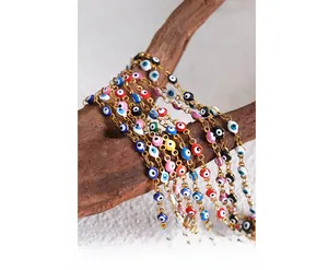 Close-up of colorful enamel evil eye charm bracelets on rustic wood branches