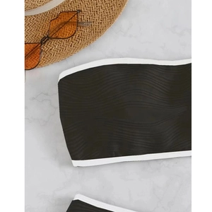 Vista piatta del bikini a fascia nero strutturato con bordo bianco e accessori da mare