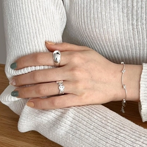 Detailed view of irregular textured 925 silver ring and wavy bracelet on hand