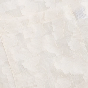 Gros plan détaillé du tissu texturé blanc du blazer en polyester avec étiquette de soin