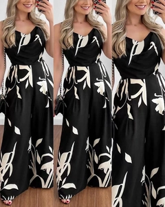 Detail of floral printed black jumpsuit featuring v-neck straps and wide-leg design