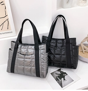 Detail of silver and black quilted puffer tote bags with broad straps and side pockets