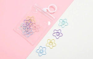 Star-shaped metal paperclips in candy colors displayed in clear packaging on pink background