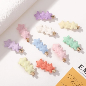Star-shaped cotton hair clips in macaron colors displayed on white surface