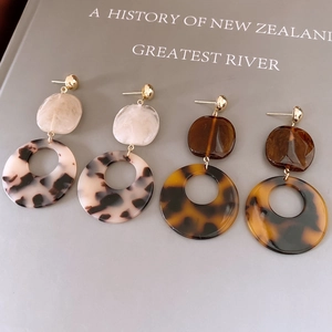 Vue détaillée des boucles d'oreilles rondes en résine à motif écaille sur un livre vintage