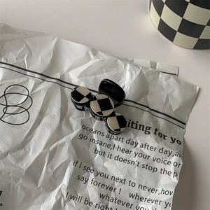 Detail view of a black and white checkerboard hair clip with three round patterns
