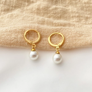 Detail of 18K gold plated hoop earrings featuring a single round white pearl pendant