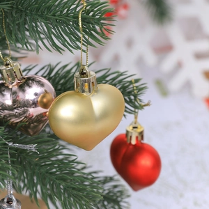 Close-up of heart-shaped Christmas ornaments in gold, rose gold and red on tree
