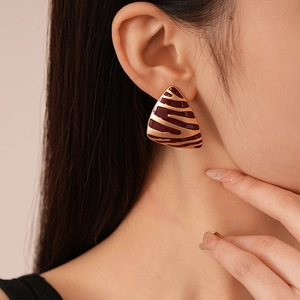Détail des boucles d'oreilles triangulaires zébrées en émail brun rouge et plaqué or