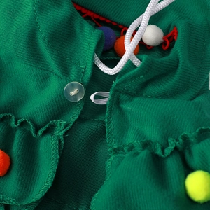 Close-up of green Christmas tree dog cloak featuring colorful pom-poms and twill texture