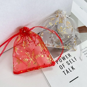 Detail of red and white organza gift bags featuring gold foil snowflake prints and drawstrings