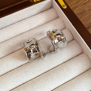 Macro shot of silver C-shaped liquid metal earrings in a velvet jewelry box
