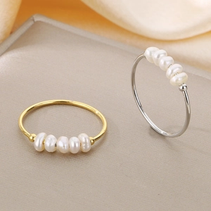 Eleganti anelli in titanio oro e argento con perle d'acqua dolce su fondo di seta