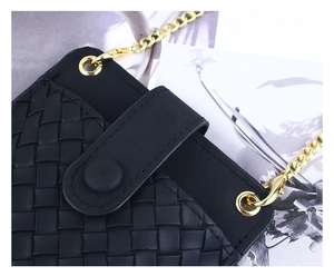 Détail d'un mini sac noir à texture tressée avec chaîne dorée et fermeture à bouton