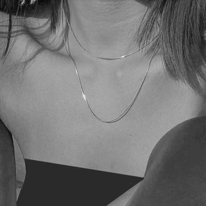 Dettaglio di una collana a doppio strato in argento minimalista su una modella donna