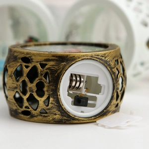 Macro detail of the base battery compartment and power switch on a bronze Christmas lantern