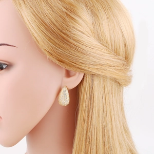 Elegant gold teardrop earrings with pave white cubic zirconia shown on model