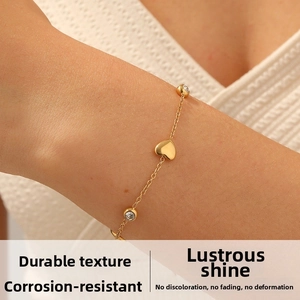 Dettaglio del bracciale in acciaio dorato con ciondoli a cuore e cristalli rotondi lucidi