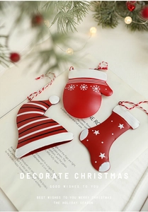 Nahaufnahme festlicher Weihnachts-Eisenanhänger mit roten Handschuhen und Socken auf Buch