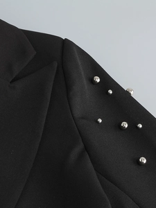 Detailed view of silver metal beads on black twill fabric of a fashion blazer shoulder