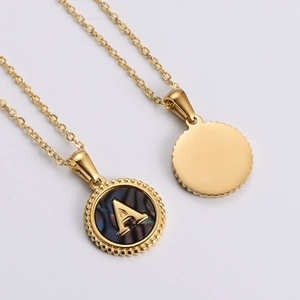 Close-up of gold round pendant necklace featuring letter A on colorful shell inlay