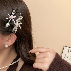 Detail of lace hair clip with pink silk bow, heart rhinestone, and faux pearls on hair