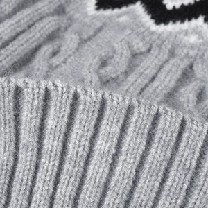 Gros plan d'un bonnet en tricot gris avec texture torsadée et pompon pour l'hiver froid