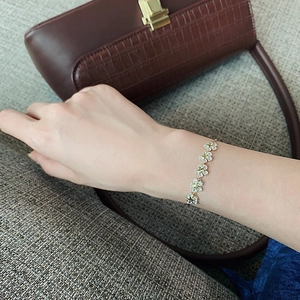 Detailed view of dainty gold flower bracelet with clear crystals on a model wrist