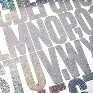 Detail of holographic silver glitter letter stickers with 3D water drop effect