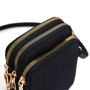 Fashionable black nylon mini crossbody phone bag with gold zippers and adjustable strap