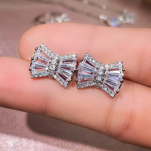 Detailed close-up of silver bow-shaped earrings featuring sparkling cubic zirconia stones