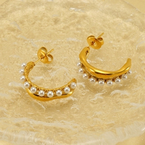 Gros plan détaillé de boucles d'oreilles dorées en C avec perles et finitions