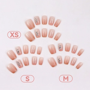 Pink gradient press-on nails with butterfly designs and rhinestones in various sizes