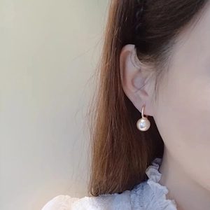 Elegant French style pearl drop earrings with gold hooks worn by a model in profile
