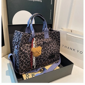 Leopard print canvas tote featuring front pockets, purple straps, and a bear charm accessory