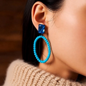 Close-up of vintage oval earring with blue gemstone and light blue beaded hoop on model