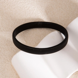 Gros plan d'un bracelet spirale noir multicouche flexible sur fond de pierre minimaliste