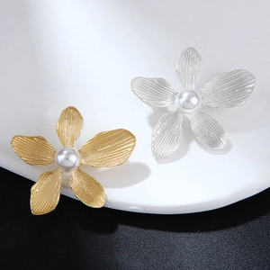 Close-up of gold and silver flower brooches with leaf textures and pearl centers
