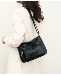 Side view of black pebble leather crossbody bag with multiple zippers on a model