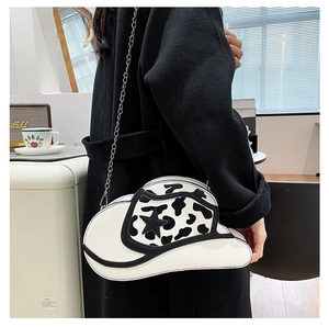 Detail of white cow print cowboy hat shaped shoulder bag with silver chain and star patterns