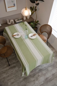 Close-up of green and beige striped cotton linen tablecloth in a cozy home dining setting