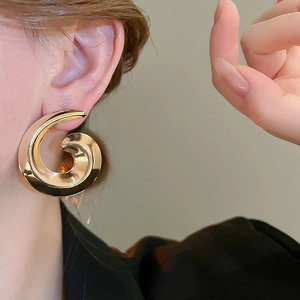 Macro shot of large golden spiral swirl earrings with high-polish metallic finish