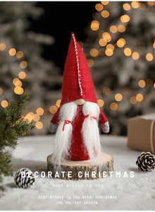 Detail of Christmas gnome plush on wood base with festive bokeh lights and pine cone